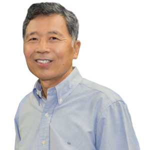 Mature asian man with short gray hair wearing a light blue button down shirt.