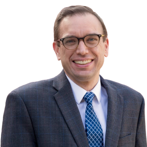 Mature white man with short brown hair wearing glasses and a suit jacket with a blue tie.