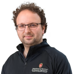 white man with curly brown hair and glasses