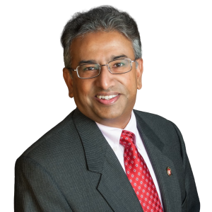 Mature Indian man wearing glasses and a red tie.