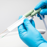 Image of the NeuWave device that looks like two needs encased in a white case and held in two hands.