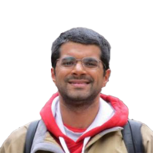 Man with black facial hair and hair wearing a red sweatshirt and tan jacket.