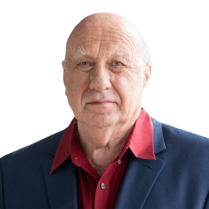 Mature white man with no hair and wearing a red shirt with a navy suit jacket.