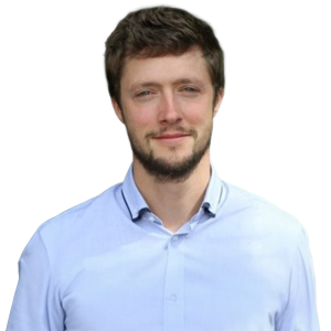 Man with dark brown hair and facial hair wearing a light blue button down shirt.