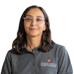 Mature indian woman with medium length brown hair wearing glasses and a gray polo shirt.