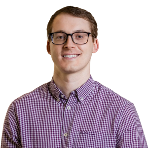 white man with short brown hair wearing glasses and a red plaid button down shirt.