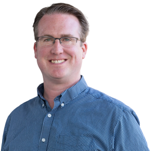 White man with short light brownish gray hair wearing glasses and a blue button down shirt.