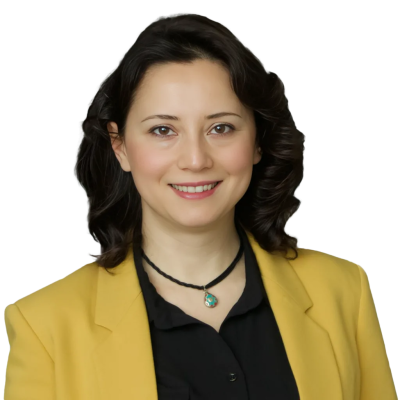 White woman with medium length black hair wearing a black shirt and yellow suit jacket.