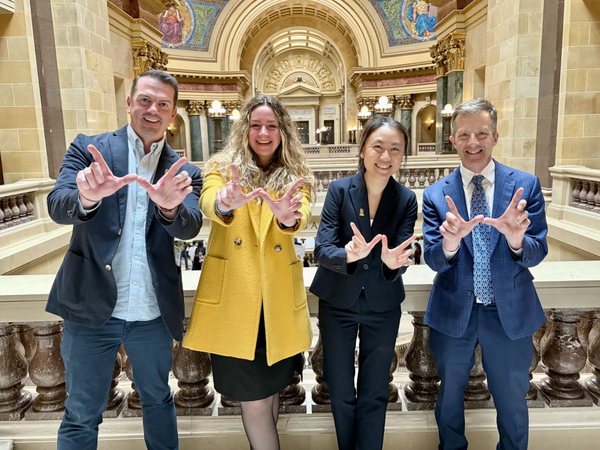 group of people in a government building holding up Ws with their hands