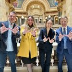 group of people in a government building holding up Ws with their hands