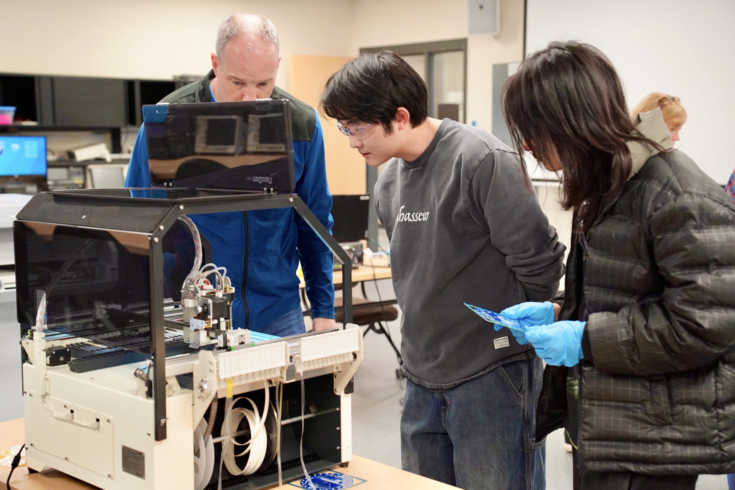 an instructor demonstrates an engineering process to two students