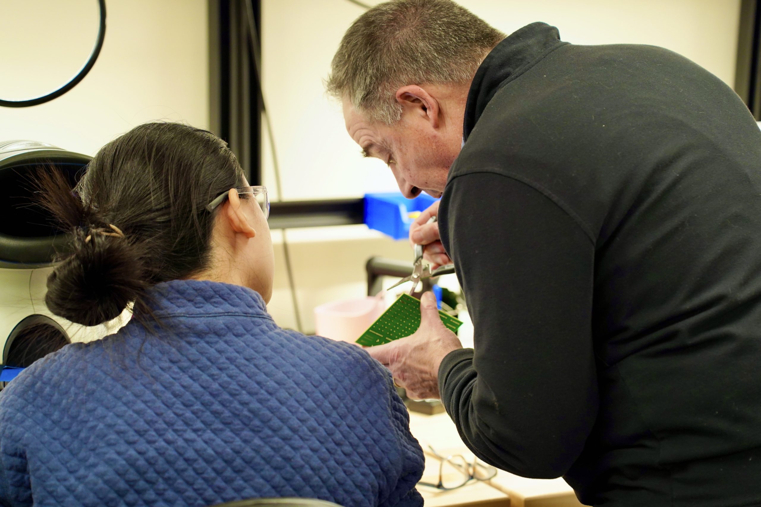 a professor instructs a student on soldering technique