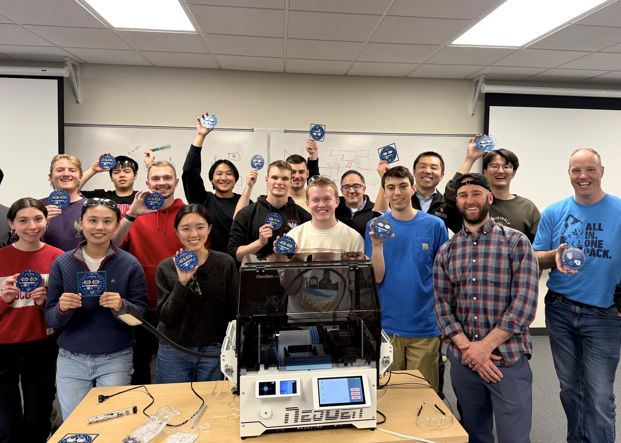 group of people posing and holding up small electronic circuits
