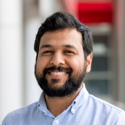 headshot of a south asian man with short black hair and a beard