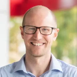 headshot of a white man with a buzzcut and glasses