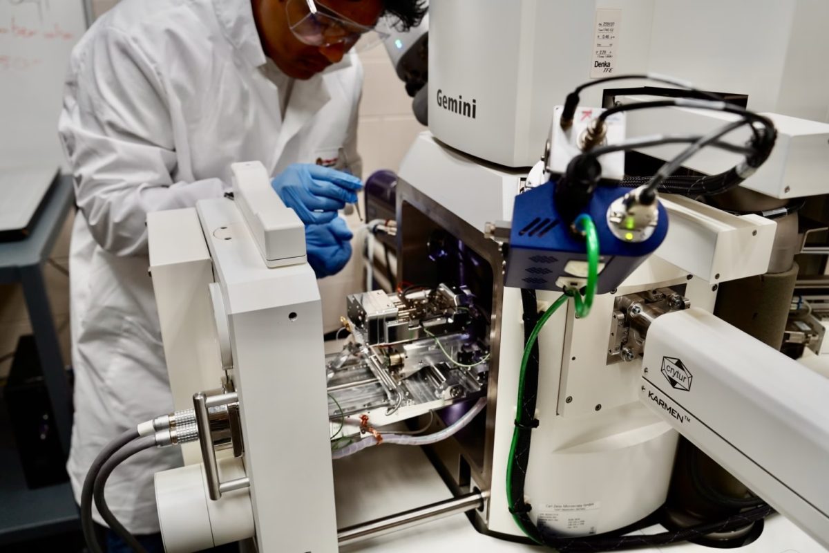 scientist leaning over a large piece of equipment