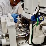 scientist leaning over a large piece of equipment