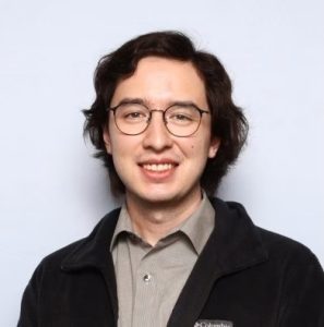headshot of a man with light skin and medium black hair with glasses