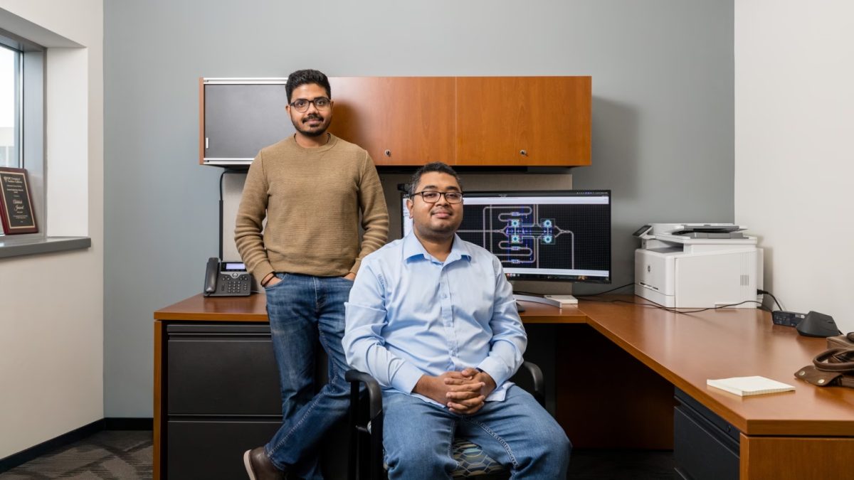 Two south Asian men sit at a desk