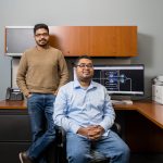 Two south Asian men sit at a desk