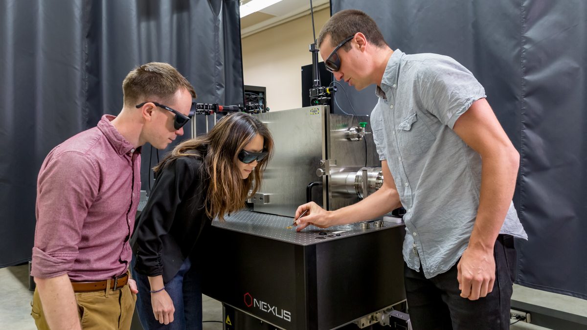 three people interacting with scientific equipment