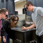 three people interacting with scientific equipment